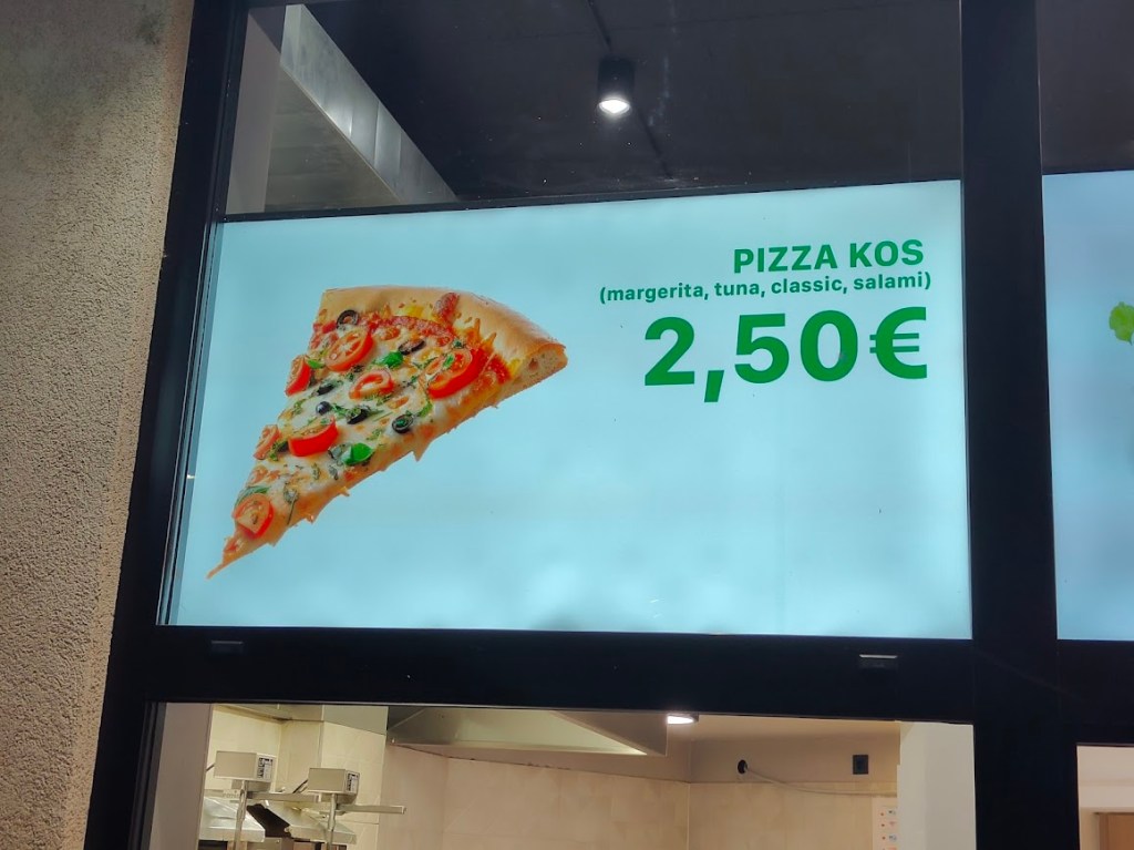 Sign featuring pizza slice with tomatoes, greens, and olives, labeled ‘PIZZA KOS’ with price 2,50 €.